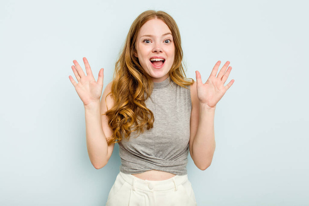 Young caucasian woman isolated on blue background receiving a pleasant surprise, excited and raising hands. - Photo, Image