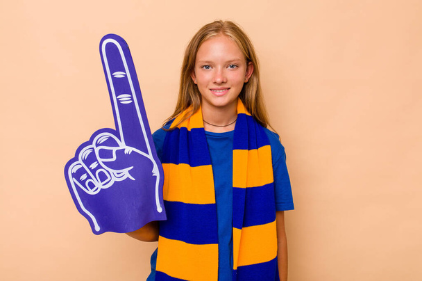 Little caucasian sports fan girl isolated on beige background happy, smiling and cheerful. - Foto, imagen