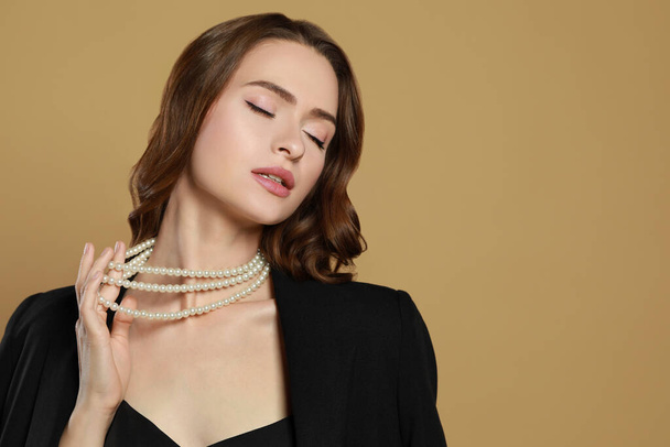 Young woman with elegant pearl necklace on brown background, space for text - Fotografie, Obrázek