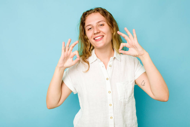 Jovem mulher caucasiana isolado no fundo azul alegre e confiante mostrando ok gesto. - Foto, Imagem