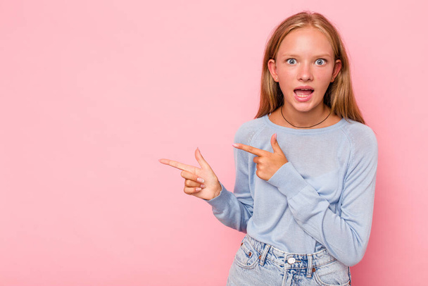 Kaukasische Teenie-Mädchen isoliert auf rosa Hintergrund zeigt mit den Zeigefingern auf eine Kopie Raum, Ausdruck von Aufregung und Wunsch. - Foto, Bild