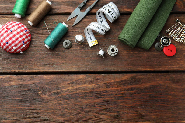 Threads and other sewing supplies on wooden table, flat lay. Space for text - Φωτογραφία, εικόνα
