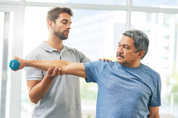 Wie fühlt sich das an? ein junger männlicher Physiotherapeut hilft einem älteren Patienten bei der Genesung - Foto, Bild
