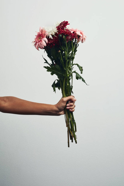 These flowers represents pure love and admiration. Studio shot of an unrecognizable woman holding a bunch of flowers against a grey background - 写真・画像