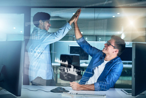 Elke dag is een overwinning. twee jonge mannelijke programmeurs werken samen aan een computer en geven elkaar 's nachts een high five op kantoor - Foto, afbeelding