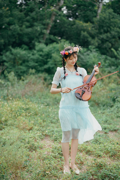 The girl is playing the violin under the big tree - Fotó, kép