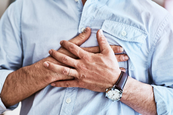 A dor está aqui. um homem irreconhecível segurando seu peito enquanto sofre com azia em casa - Foto, Imagem