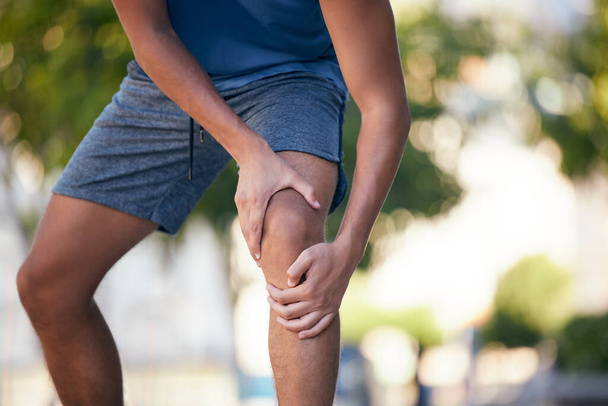Knee pain, hands and man with injury during exercise, training and running in a park, pain and inflammation. Hand, fitness and arthritis in leg of runner during workout, sport and practice outdoors. - Foto, imagen
