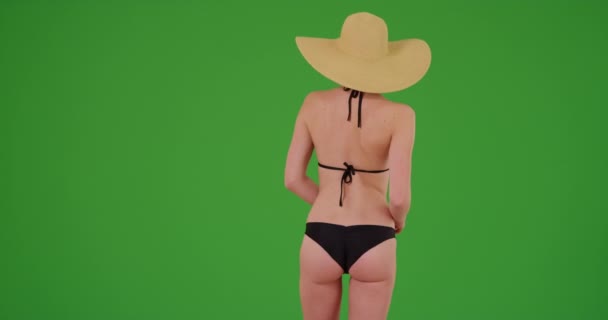 Hübsche Millennial-Frau im Urlaub mit Sonnenhut wendet sich der Kamera zu und lächelt auf dem grünen Bildschirm. Auf einem grünen Bildschirm, der getastet oder zusammengesetzt werden soll. - Filmmaterial, Video