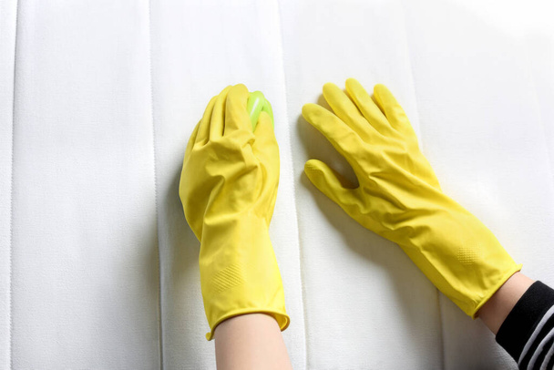 Woman in yellow gloves cleaning white mattress with brush, top view - Fotó, kép