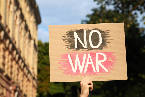 Woman holding poster with words No War outdoors - Foto, Imagen