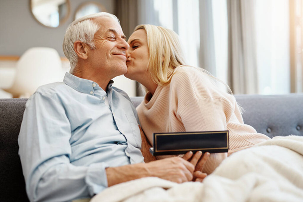 Thank you my love. mature man giving his wife a gift on the sofa at home - Fotoğraf, Görsel