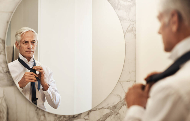 Ты лучше, чем ты сам. уверенный в себе зрелый бизнесмен, смотрящий на свое отражение в зеркале, одеваясь днем дома - Фото, изображение