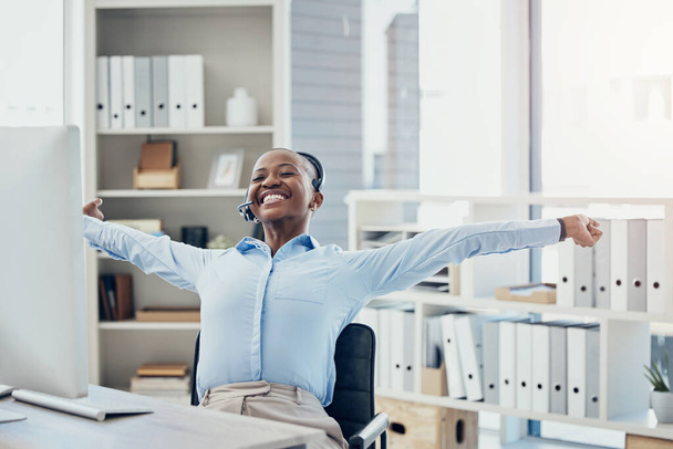 Black woman, stretching and happy call center consultant relax, smile and relief while working for crm, customer support and customer service. Woman, desk and stretch in celebration of sale success. - Photo, image