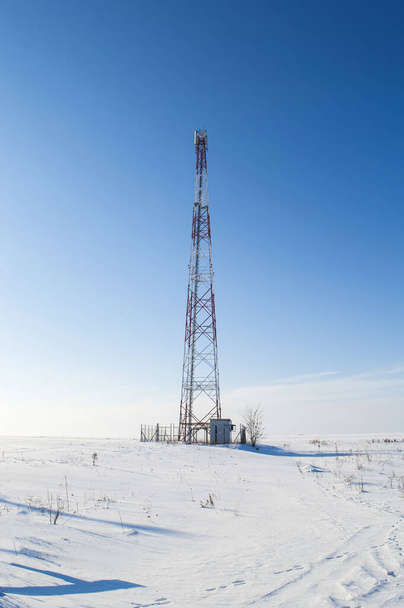 Torre móvel em um campo branco coberto de neve contra um céu azul. Torre de dados. Comunicações móveis e Internet. Equipamento industrial. Tecnologias de transmissão de dados. Temporada de Inverno. - Foto, Imagem