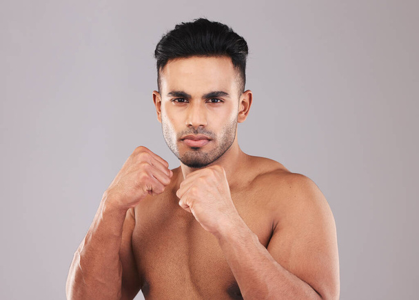 Fist, boxing and young man on studio background doing training for health, fitness and wellness with workout. Indian male, fight position and dedicated for match, motivation and energy for practice - Zdjęcie, obraz