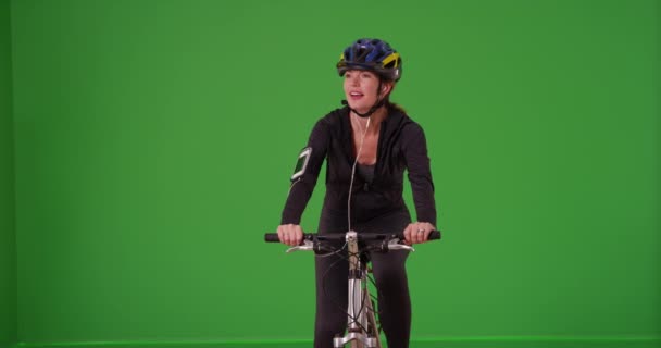 Femme d'âge moyen conduisant joyeusement son vélo vers la caméra avec un casque sur l'écran vert. Sur écran vert à saisir ou à composer. - Séquence, vidéo