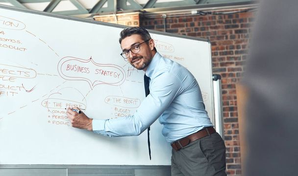 Ensuring everyone understands the big plan. a mature businessman using a whiteboard during a presentation in an office - Photo, image