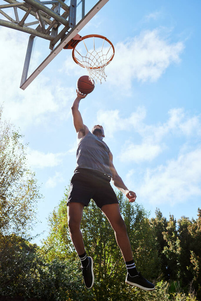 Basketball, black man and shooting, athlete and fitness, playing sports on outdoor basketball court and jumping. Active, exercise and sport with muscle, strong and training with workout in nature - Photo, image