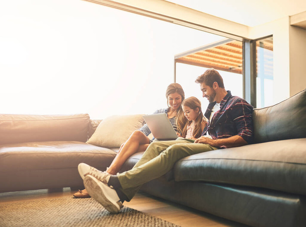 É hora de aprender sobre tecnologia. uma mãe e um pai usando um laptop com sua filha no sofá em casa - Foto, Imagem