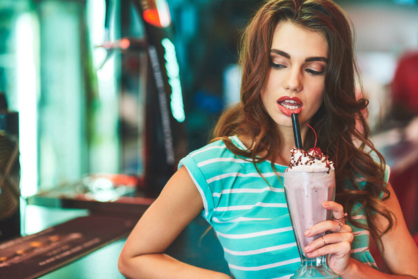Sprawia, że koktajl mleczny wygląda seksownie. piękna młoda kobieta pijąca shake 'a w knajpie - Zdjęcie, obraz