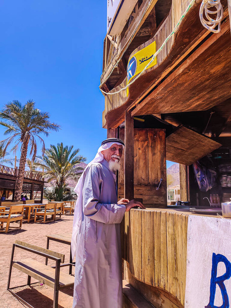 Viejo beduino con barba blanca de pie junto a la barra de café  - Foto, Imagen