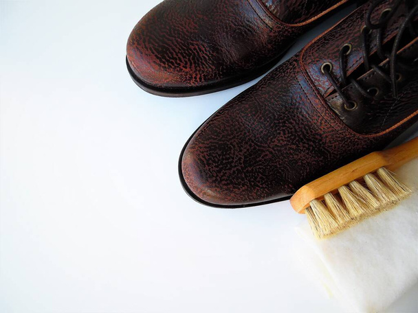 Мужская обувь и щетка для обуви на светлом фоне. Уход за кожей, чистка обуви - Фото, изображение