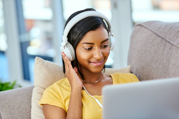 Ráda se dívám na novou hudbu. dospívající dívka poslouchající hudbu a pomocí notebooku doma - Fotografie, Obrázek