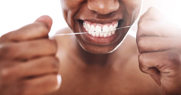 Her zaman düzenli olarak diş ipi kullanmayı unutma. Evdeki banyoda diş ipi kullanan tanınmayan genç bir adam. - Fotoğraf, Görsel