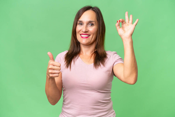 Middelbare leeftijd blanke vrouw over geïsoleerde achtergrond met ok teken en duim omhoog gebaar - Foto, afbeelding