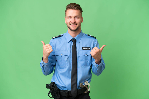 Молодий поліцейський над ізольованим тлом з великими пальцями вгору жестом і посмішкою
 - Фото, зображення