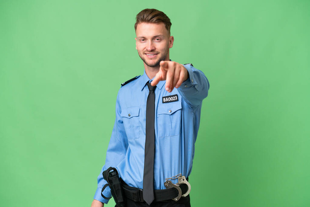 Giovane poliziotto su sfondo isolato punta il dito contro di te con un'espressione sicura - Foto, immagini