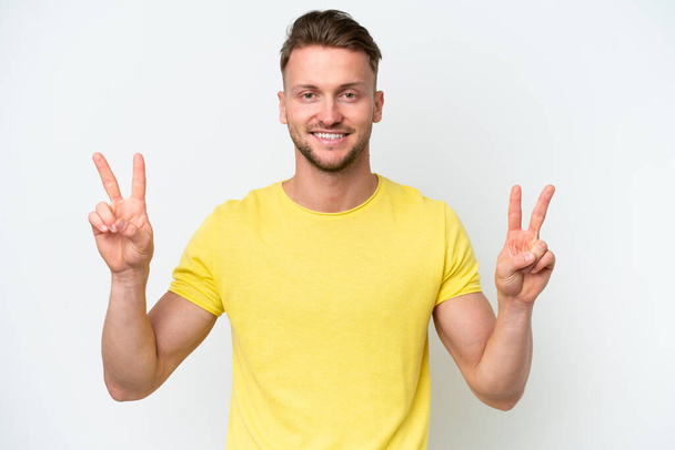 Young blonde caucasian man isolated on white background showing victory sign with both hands - Photo, Image