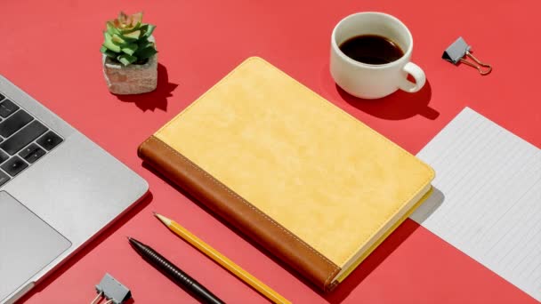Στο γραφείο του σπιτιού σε ένα κόκκινο τραπέζι ένα σημειωματάριο ένα στυλό ένα μολύβι και ένα φλιτζάνι καφέ. - Πλάνα, βίντεο