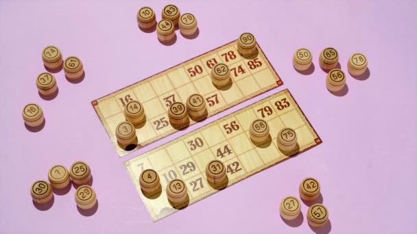 Επιτραπέζιο παιχνίδι loto για οικιακή ψυχαγωγία. Σε μωβ φόντο, βαρέλια με αριθμούς και κάρτες σε μωβ φόντο και πάνω όψη. - Πλάνα, βίντεο
