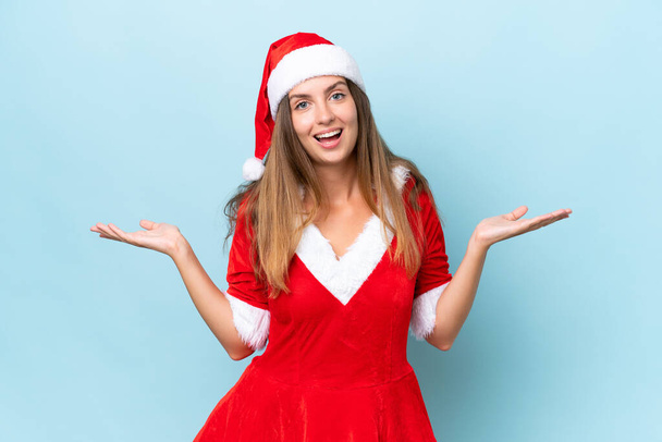 Anne Noel gibi giyinmiş beyaz bir kadın mavi arka planda şok olmuş bir yüz ifadesiyle izole edilmiş. - Fotoğraf, Görsel