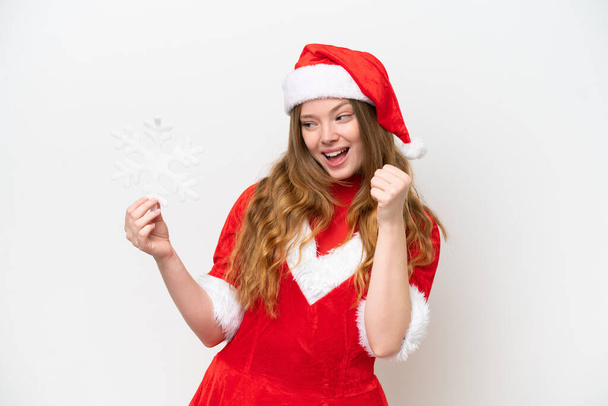 Young caucasian woman with Christmas dress holding snowflake isolated on white background celebrating a victory - Foto, afbeelding