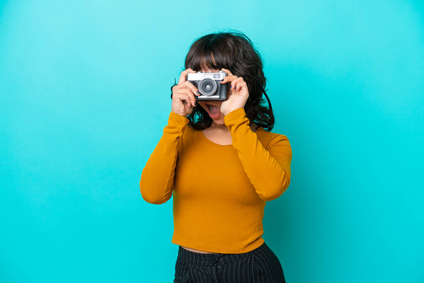 Young photographer latin woman isolated on blue background - Foto, Imagen