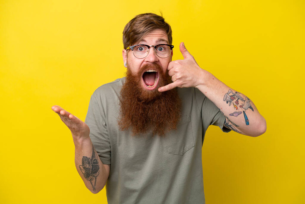 Rotschopf Mann mit Bart isoliert auf gelbem Hintergrund w machen Handygeste und Zweifel - Foto, Bild