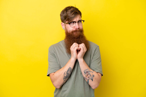 Punapää mies parta eristetty keltainen tausta juonittelua jotain - Valokuva, kuva