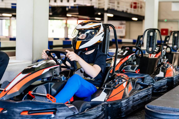 teenage boy in a racing helmet gets ready to race. Indoor kart track - Foto, Bild