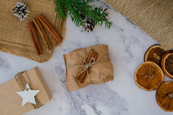 Woman making Box with New Year's gifts, wrapped in craft paper and decorated with cinnamon sticks. Holidays and Gifts concept. Handmade Eco friendly alternative green Christmas presents zero waste Sustainable lifestyle Top view - Photo, Image