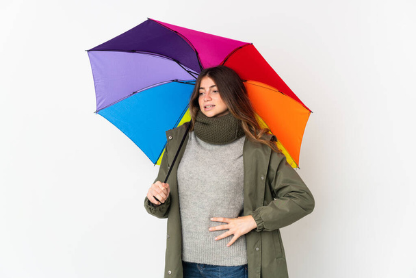Junge kaukasische Frau hält einen Regenschirm isoliert auf weißem Hintergrund und leidet unter Rückenschmerzen, weil sie sich bemüht hat - Foto, Bild