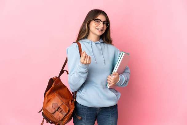 Junge Studentin isoliert auf rosa Hintergrund macht Geld Geste - Foto, Bild
