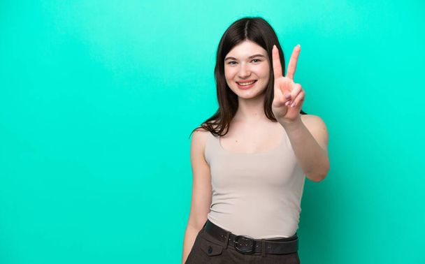 Young Russian woman isolated on green background smiling and showing victory sign - Photo, Image
