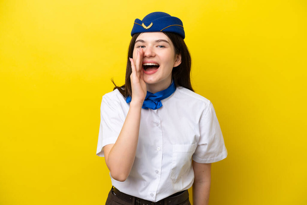 Uçak hostesi Rus kadın izole edilmiş sarı arka planda ağzı açık bağırıyor. - Fotoğraf, Görsel