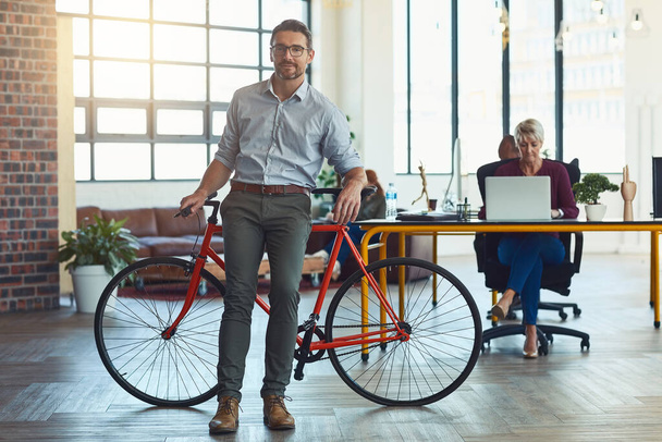 Preferiamo mantenere un ambiente informale ufficio. Ritratto di un designer maturo in piedi in un ufficio con la sua bicicletta - Foto, immagini