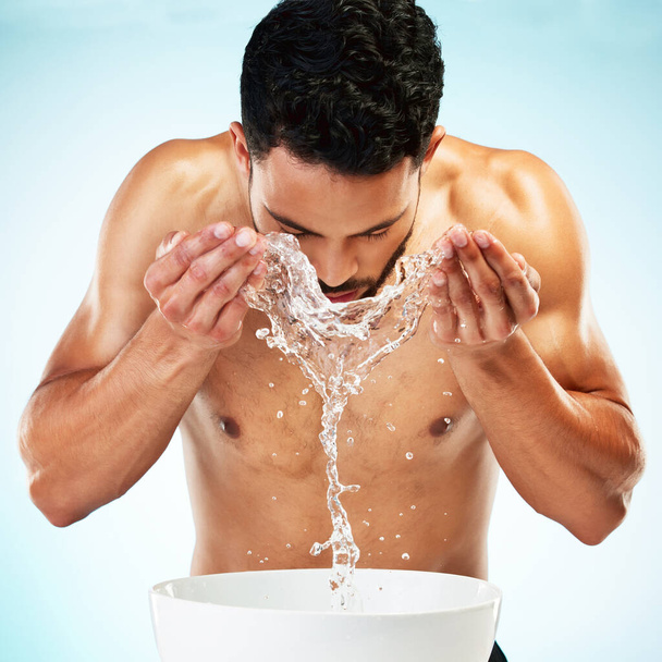 Water splash, studio en man cleaning face in een dagelijkse verzorging ochtend routine voor een gezonde huidverzorging. Schoonheid, welzijn en jong mannelijk model wassen of verzorgen in zelfverzorging behandeling. - Foto, afbeelding