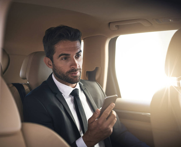 Business is calling and he will answer. a handsome young businessman sending a text message while on his morning commute to work - Foto, immagini