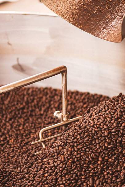 Roasting coffee beans in a professional old coffee roasting machine or roaster, close up, vertical - Photo, Image